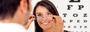 woman trying on eye glasses after receiving eye glasses exam